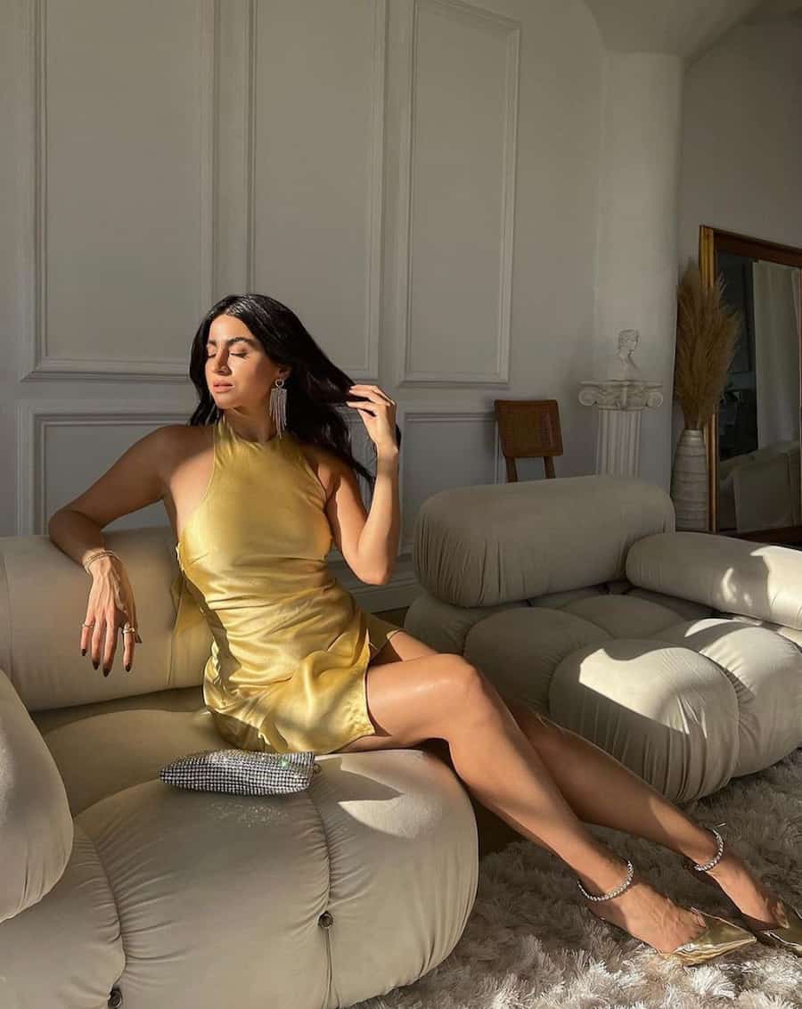 woman wearing a yellow silk halter mini dress with gold pumps