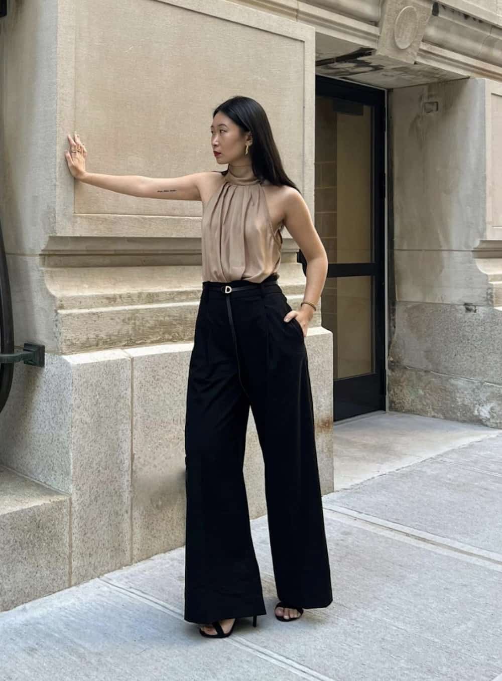 Woman wearing black wide leg trousers and a silk high neck tank.