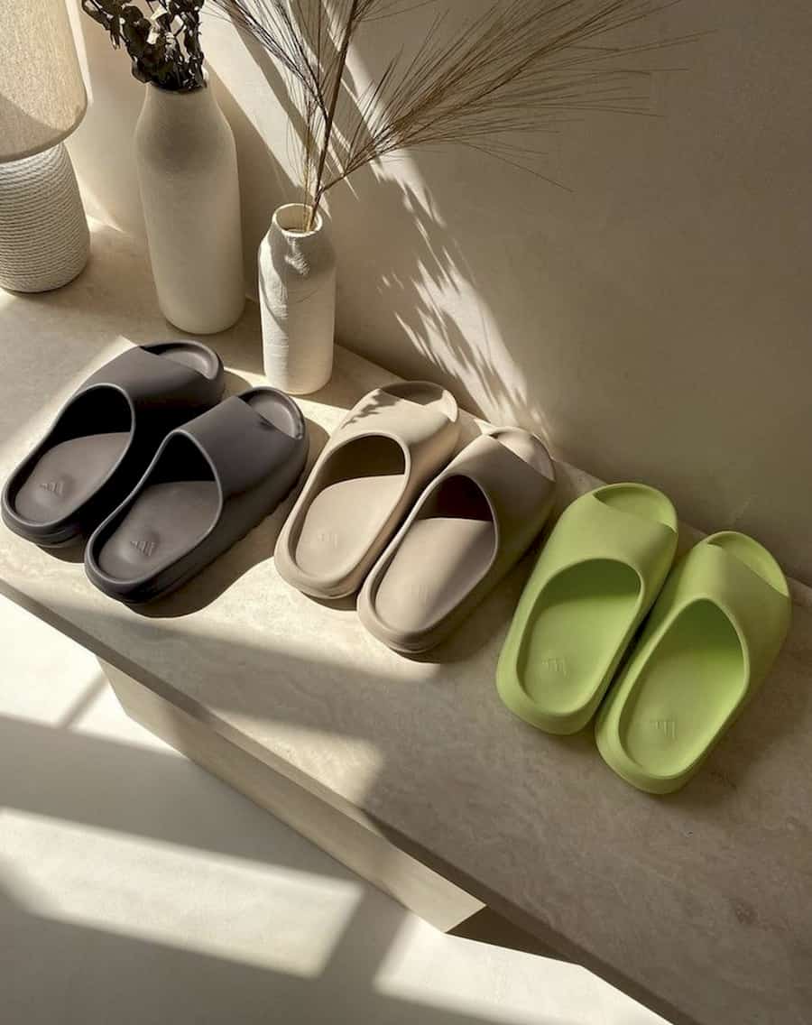 aesthetic image of three pairs of Yeezy slides lined up on a bench