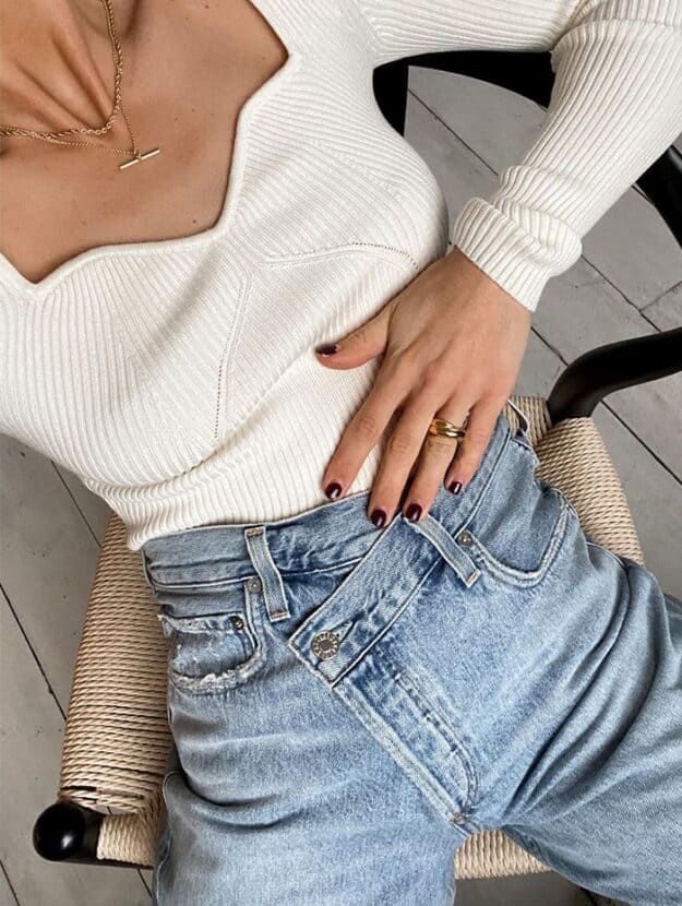 woman wearing a white ribbed knit sweetheart bodysuit with criss cross jeans