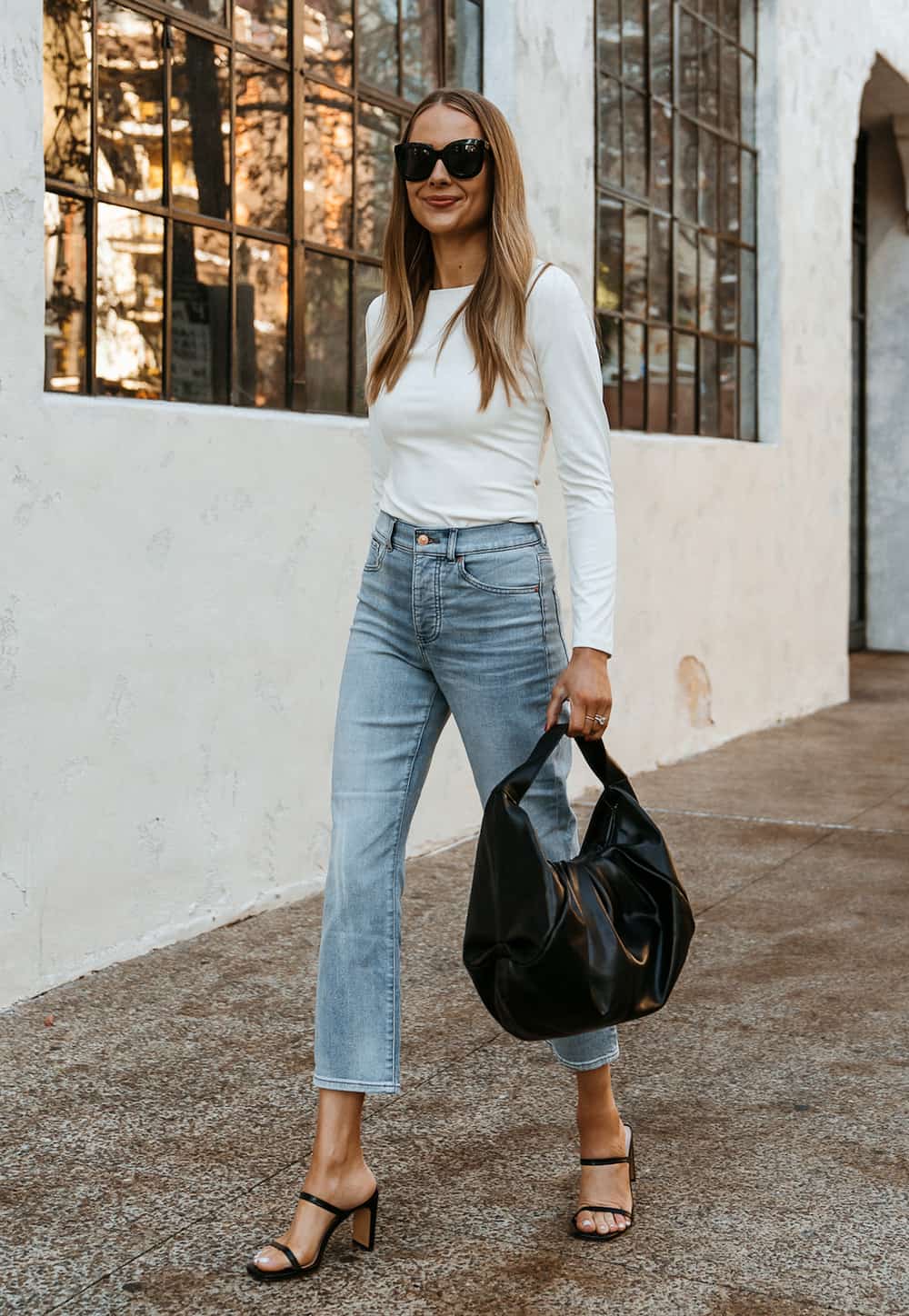 woman wearing a long-sleeve white crewneck bodysuit with jeans and black heels