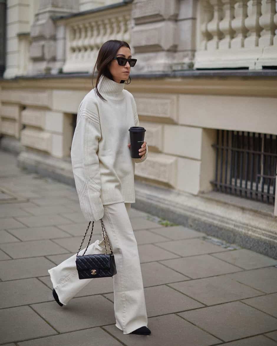 woman wearing a cream turtleneck sweater with off white bootcut jeans and black shoes