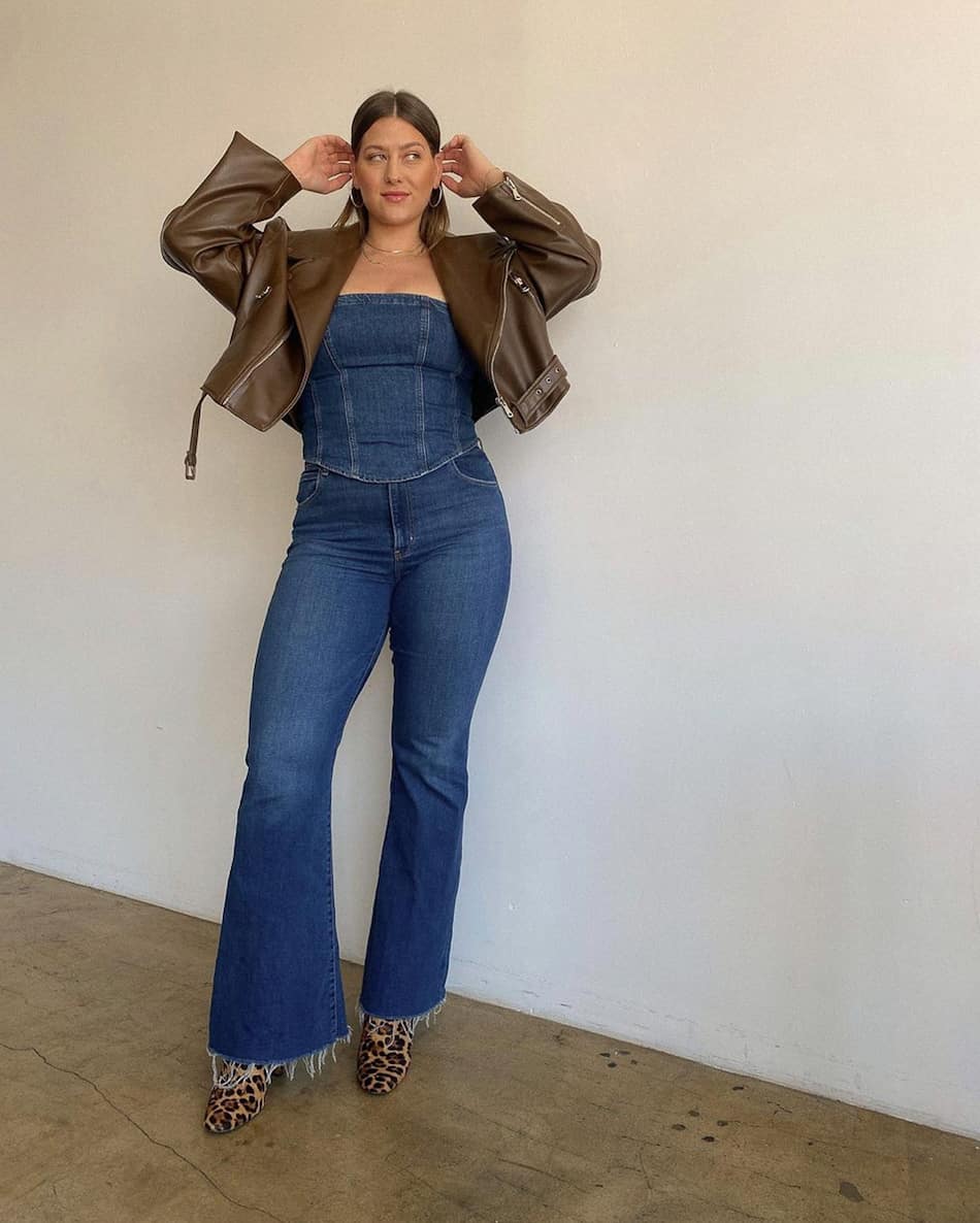 mid-size woman wearing a denim bustier top with bootcut jeans and a cropped jacket with leopard boots