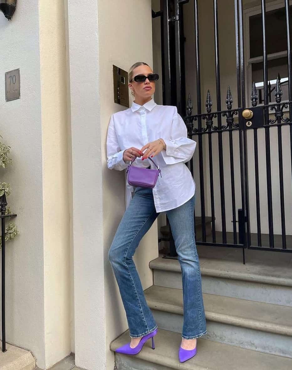 woman wearing a white button-down shirt with blue bootcut jeans and purple pumps