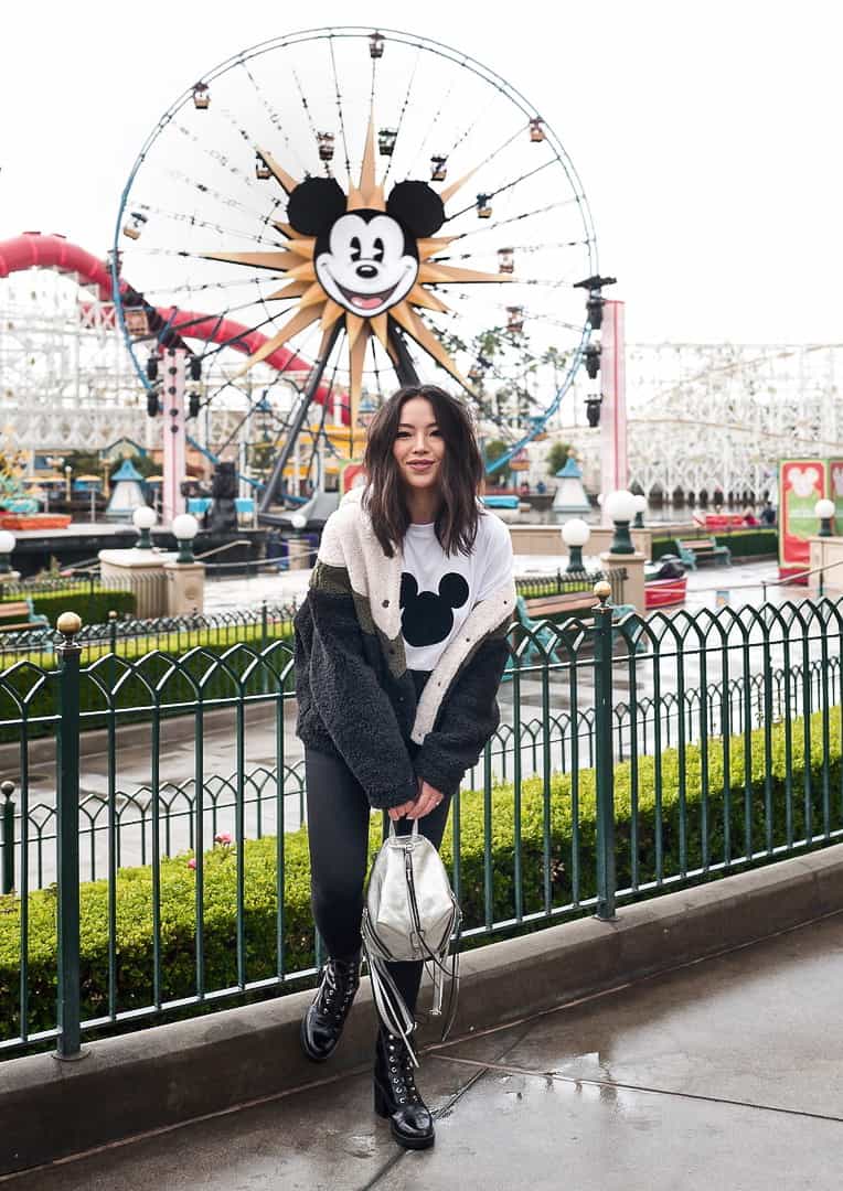 woman at Disneyland wearing a fleece jacket, Mickey Mouse t-shirt, black jeans, and combat boots