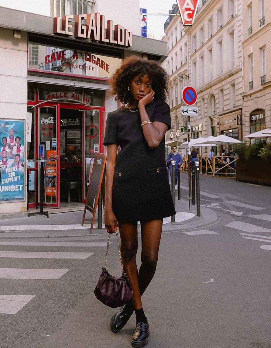 beautiful black woman wearing a mini tweed dress with sheer black stockings and loafers