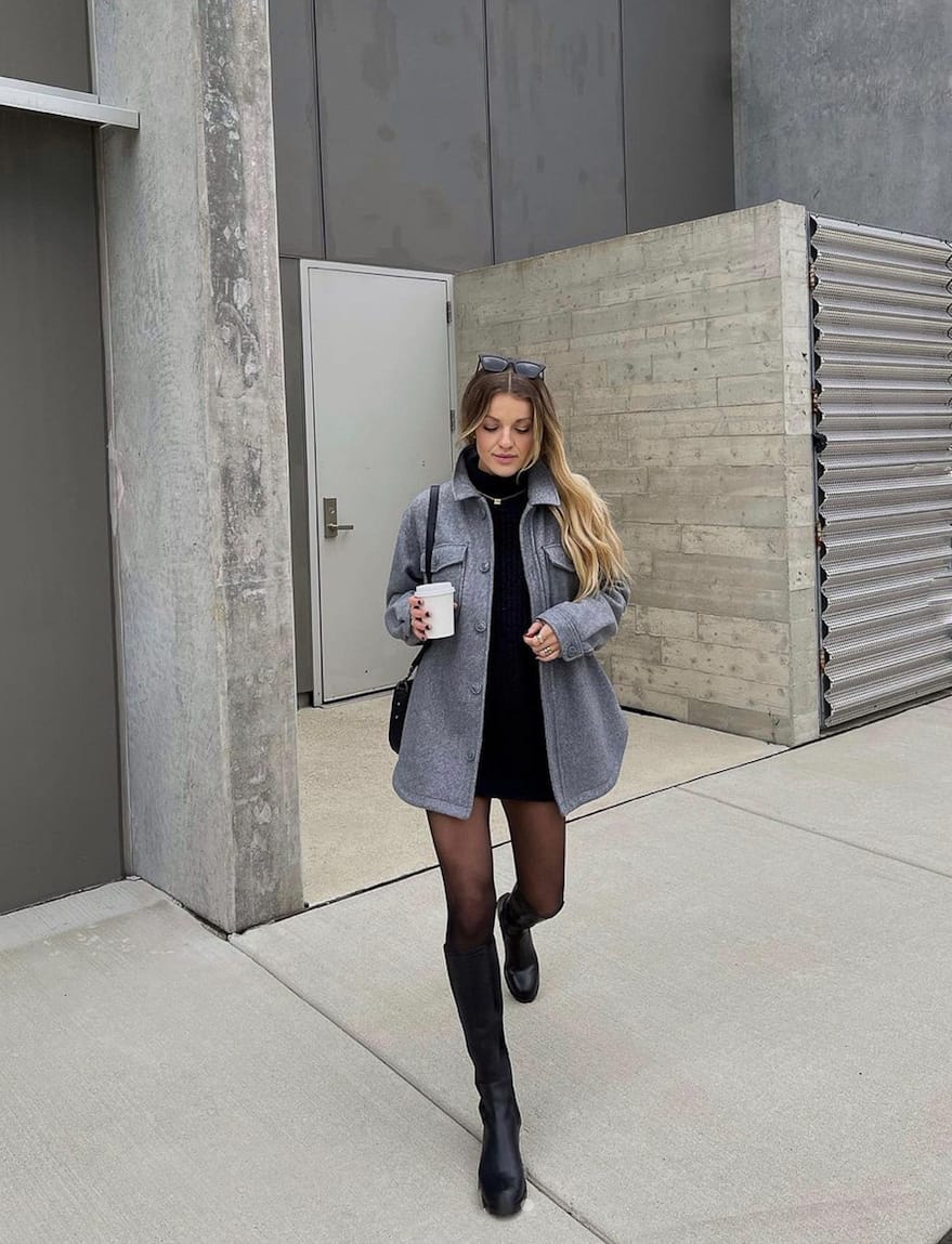 woman wearing a grey wool shacket with a black dress and sheer black stockings and black knee-high boots