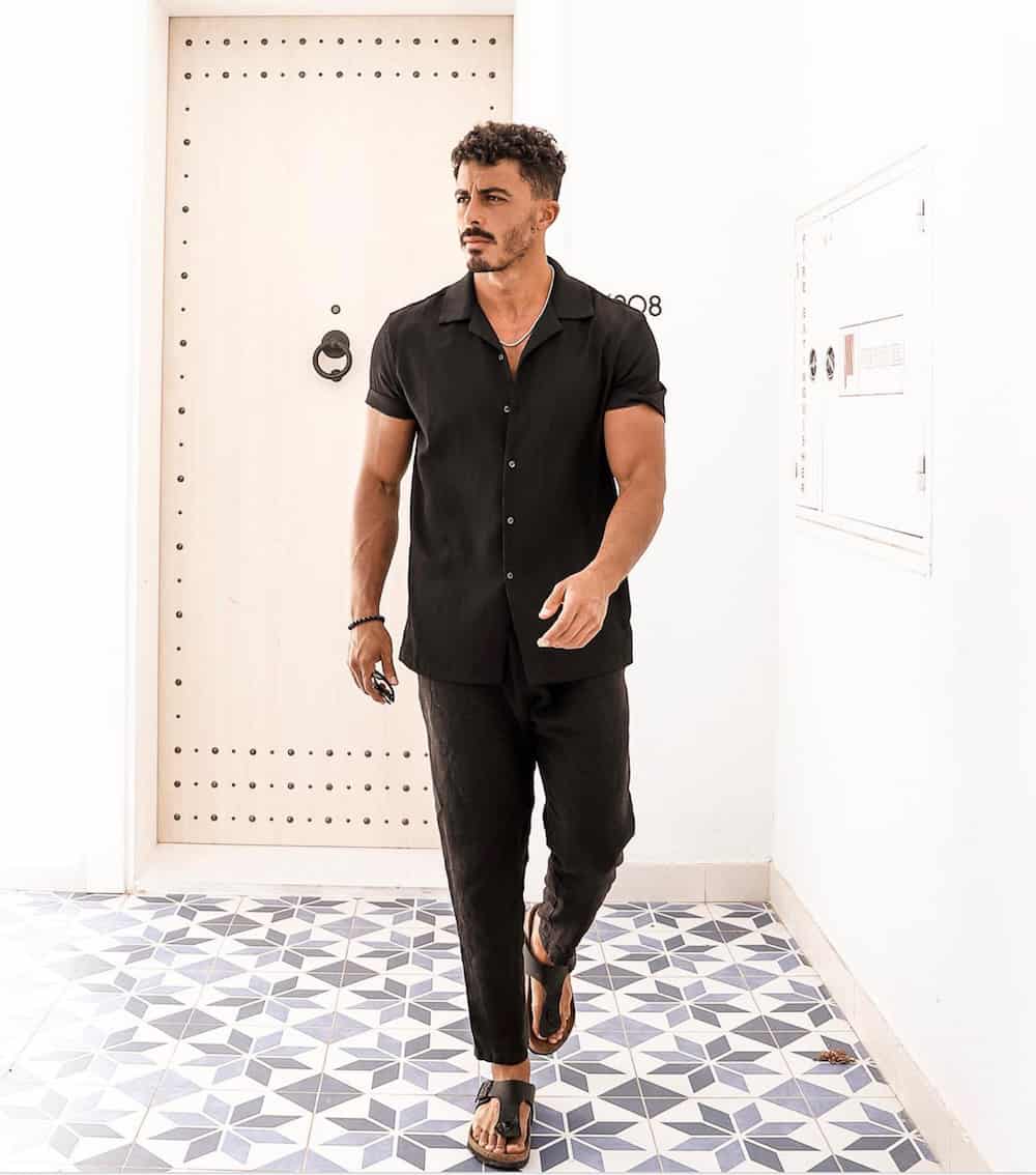 man wearing a linen black button up shirt with black linen pants and sandals