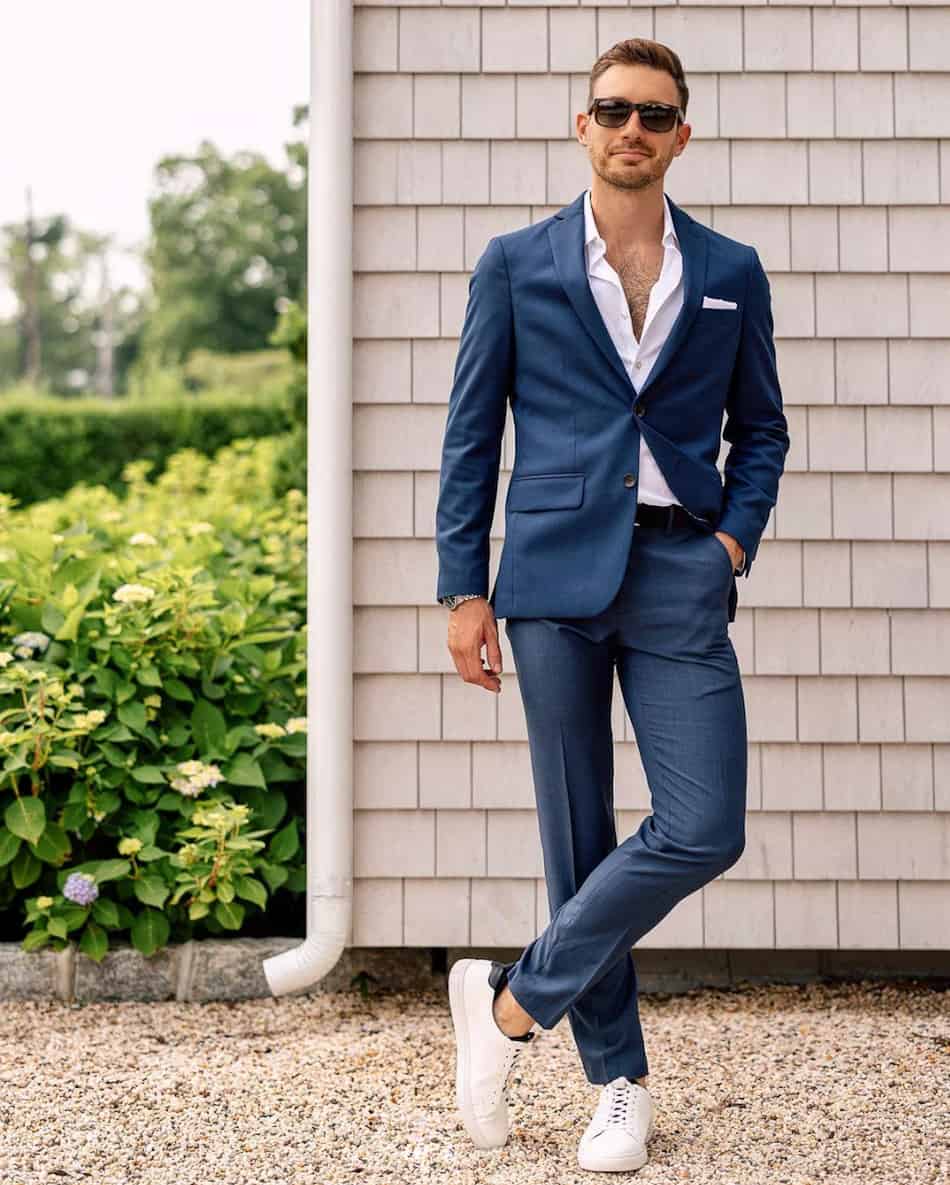 stylish man wearing a dark blue suit with a white shirt and white sneakers