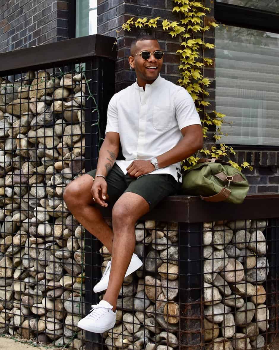 black man wearing a white button up shirt with shorts and white sneakers