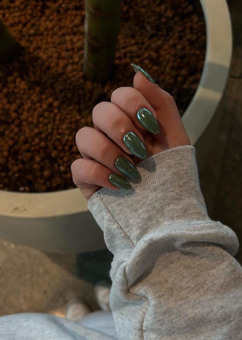 image of a hand with olive green chrome nails