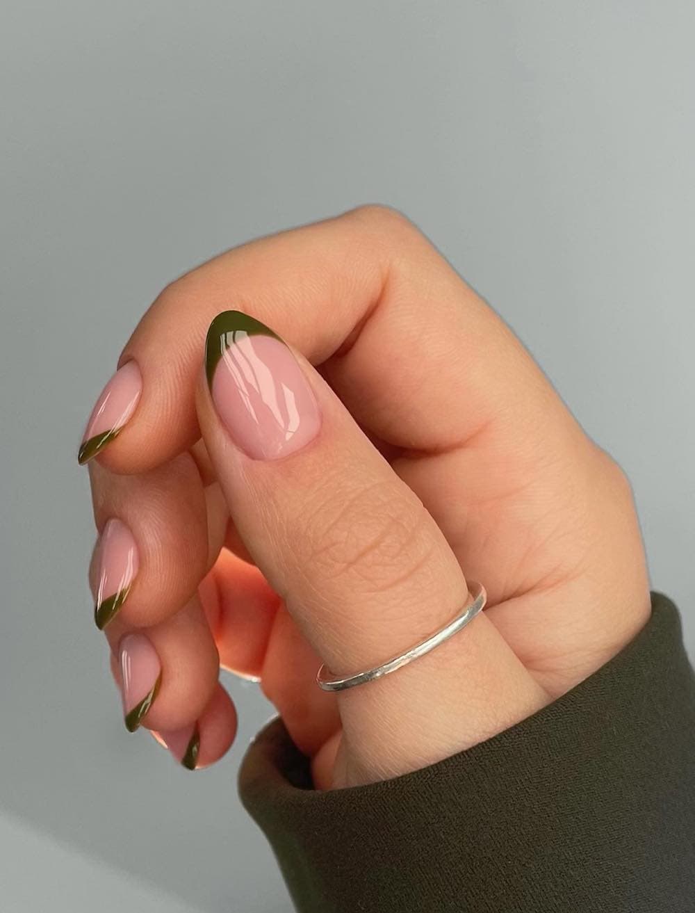 image of a hand with nude nails and olive green french tips