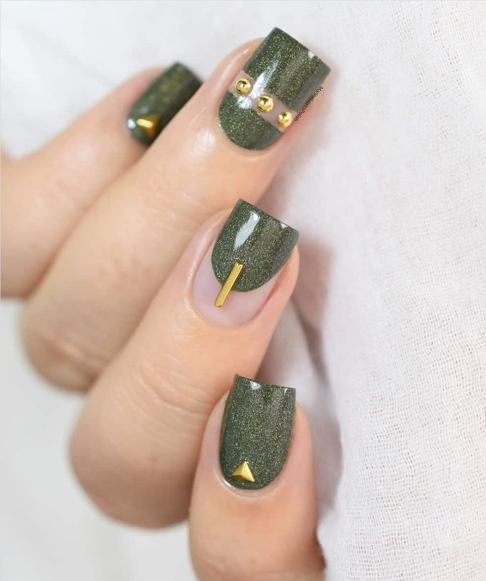 Mano con uñas cortas y cuadradas con esmalte verde oliva y detalles dorados.