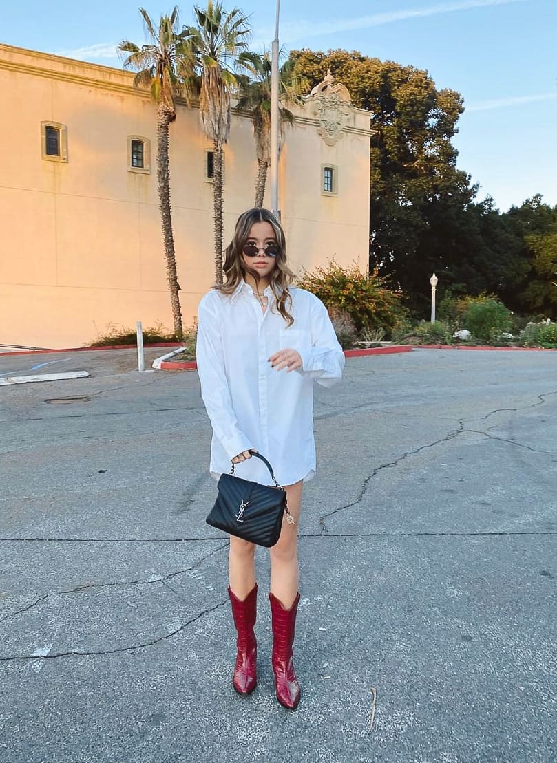 woman wearing an oversized white button-up shirt with red cowboy boots and a black YSL purse