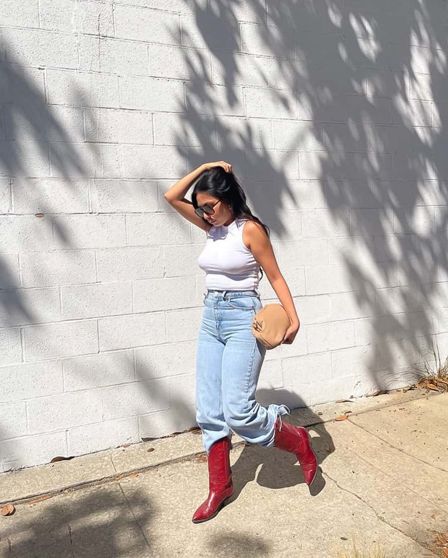 woman wearing a white tank top, blue jeans, and red cowboy boots