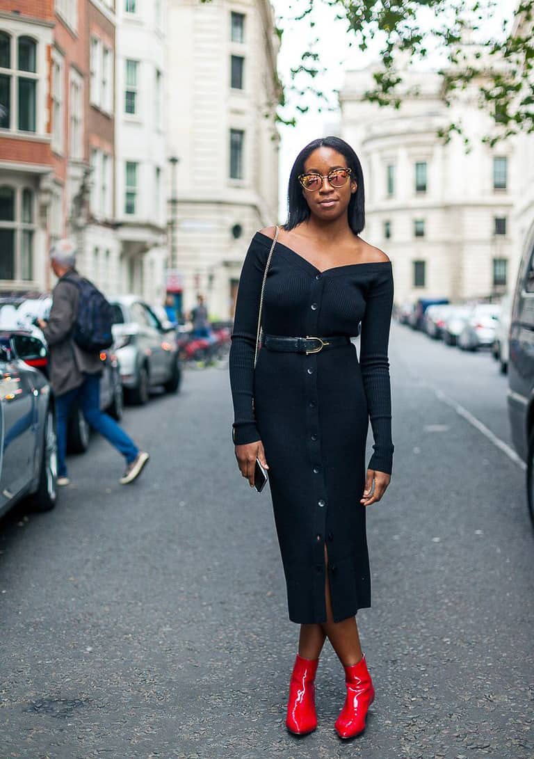 black woman wearing a body-con black button-front midi dress with red ankle boots