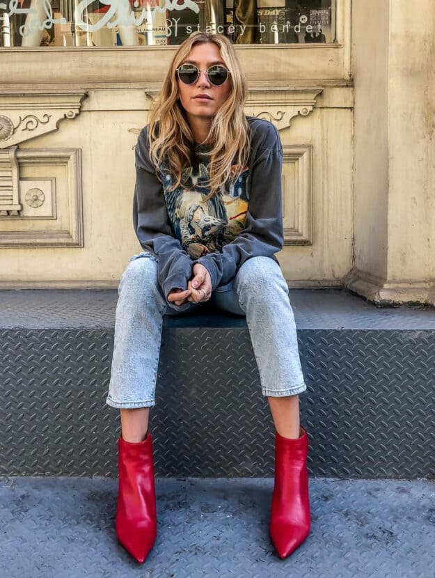 woman wearing a graphic sweatshirt with jeans and red leather ankle boots