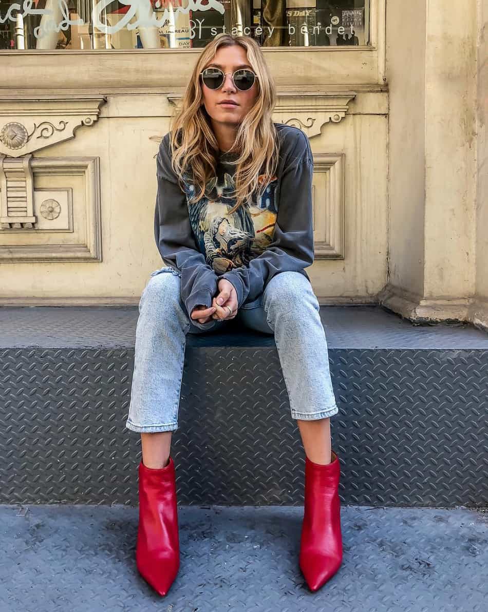 woman wearing a graphic sweatshirt with jeans and red leather ankle boots