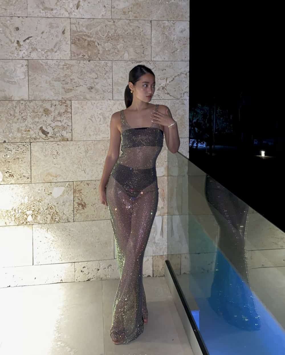 woman wearing a sexy long sheer rhinestone maxi dress over a black two piece bra and panties set