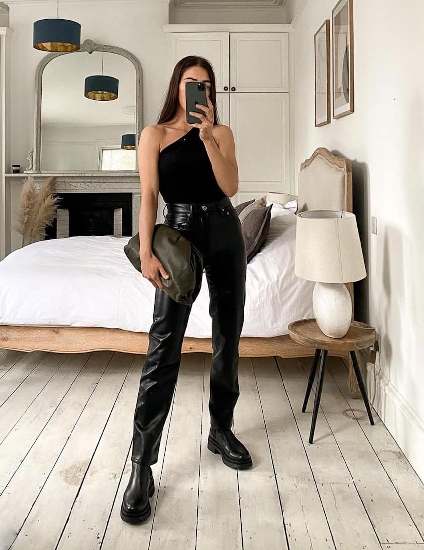 woman wearing an asymmetrical one-shoulder black tank top with leather pants and boots