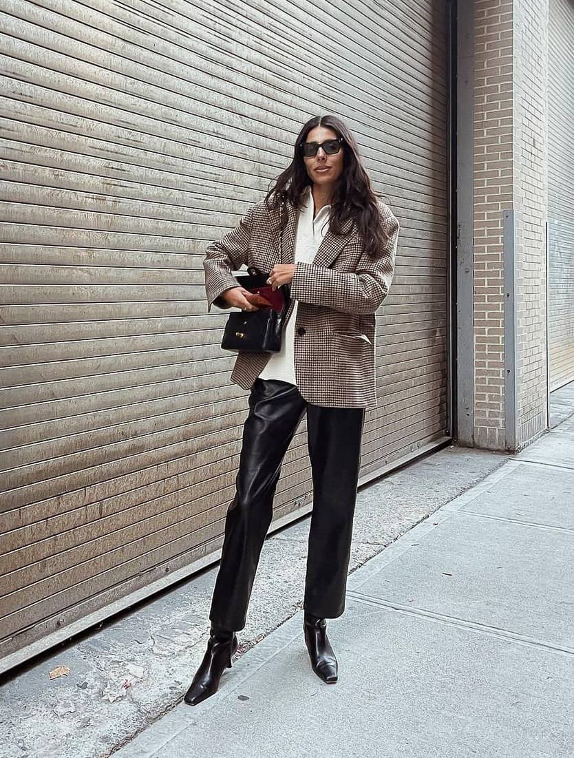 woman wearing an oversized plaid blazer coat with a sweater, leather pants, and boots