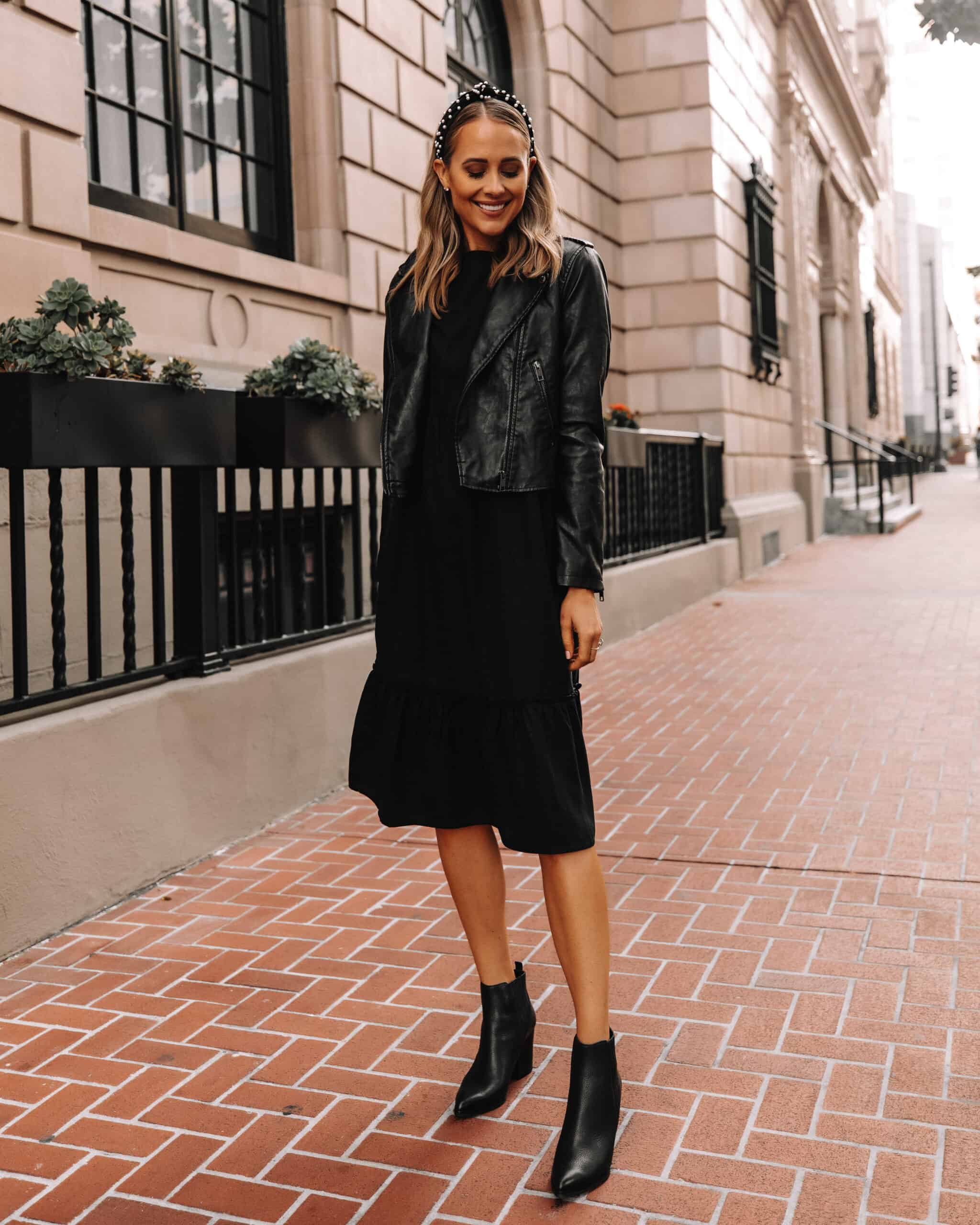 woman wearing a black leather jacket over a black midi Dress with black western ankle boots