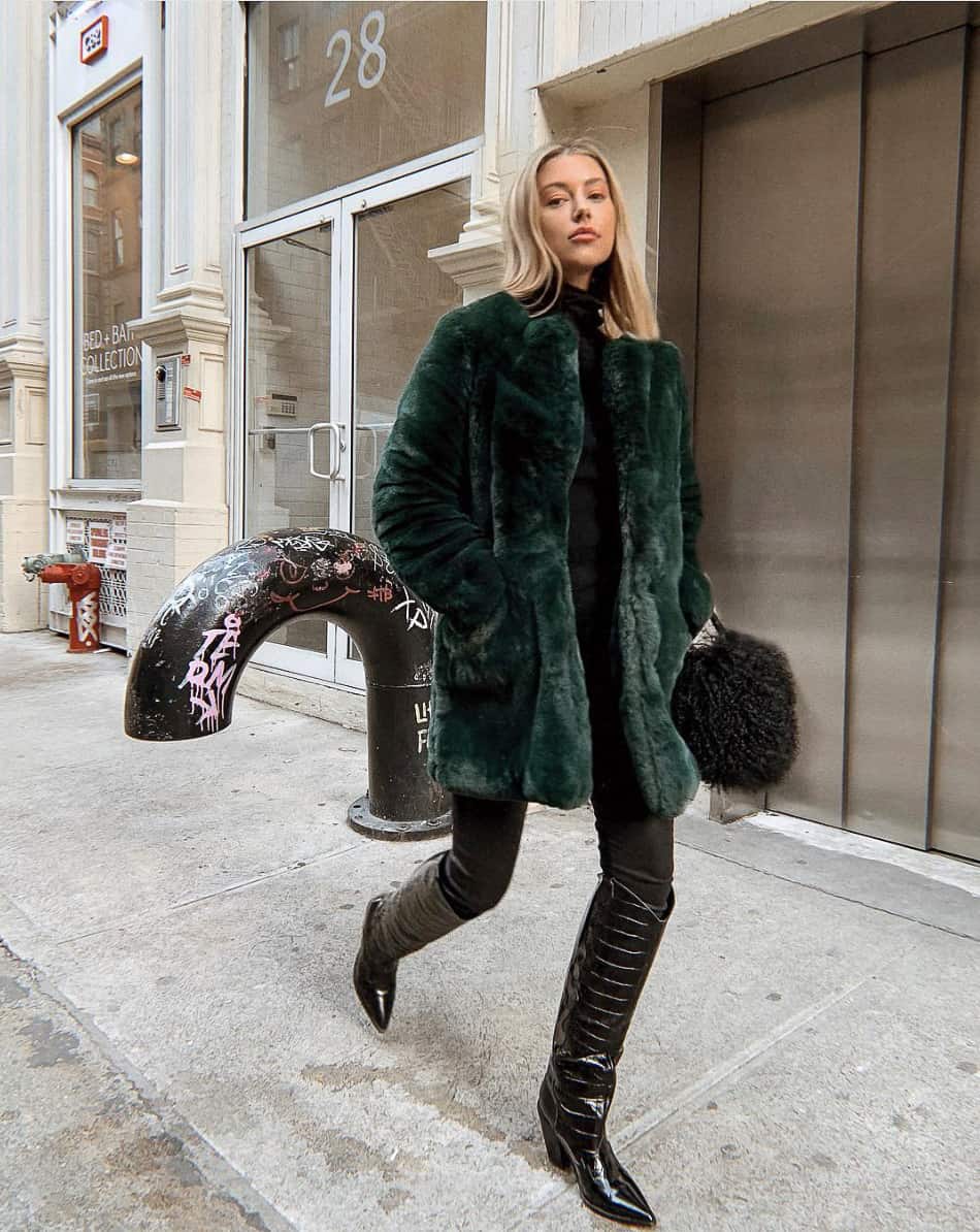 woman wearing a green faux fur coat with black pants and knee-high black croc-effect boots