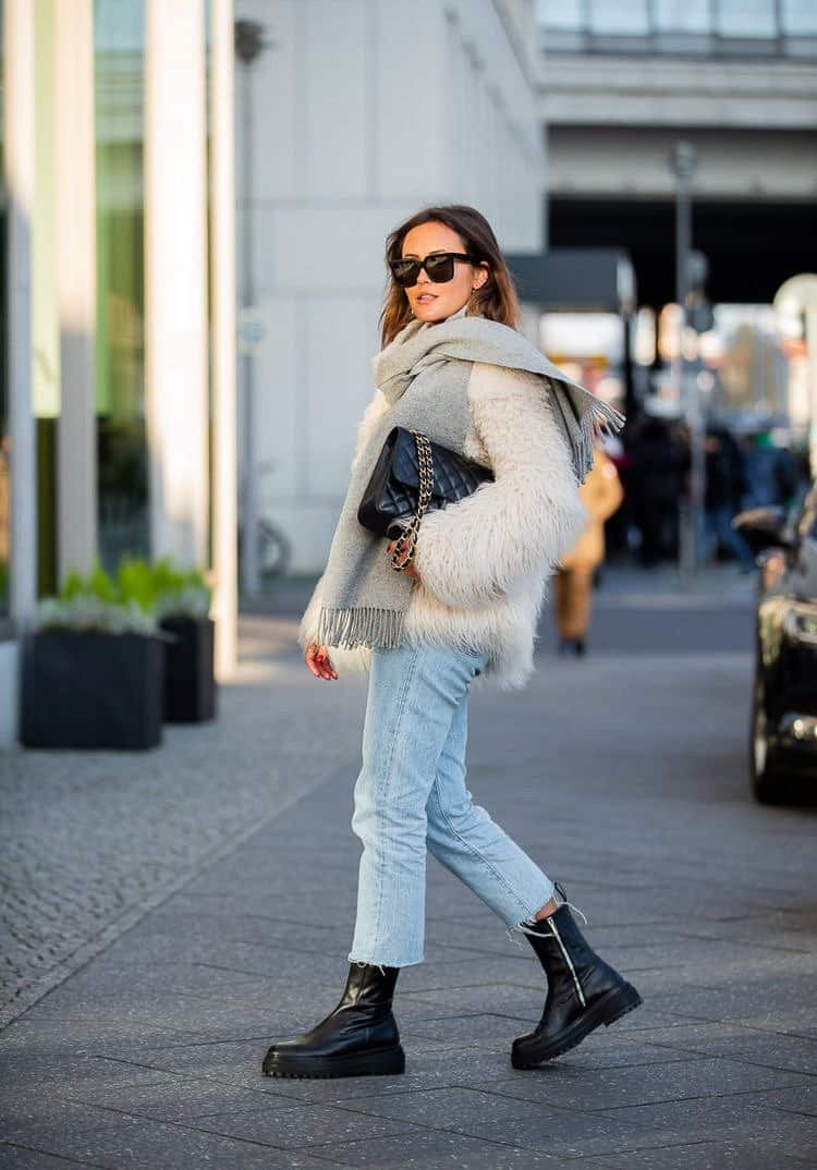 woman wearing a fuzzy ivory winter coat with blue jeans and black boots