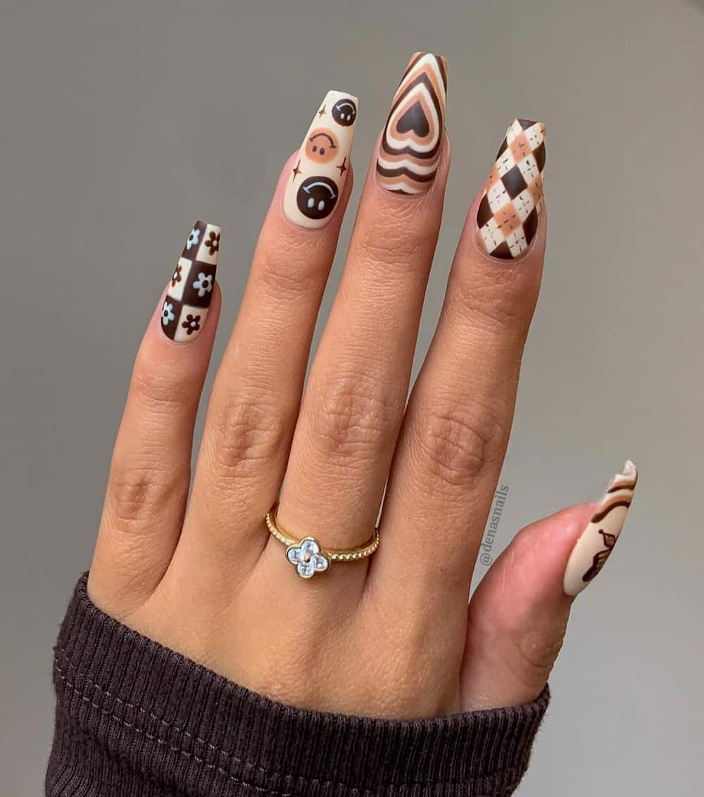 image of a hand with 70s inspired brown and cream long almond nails with fun designs
