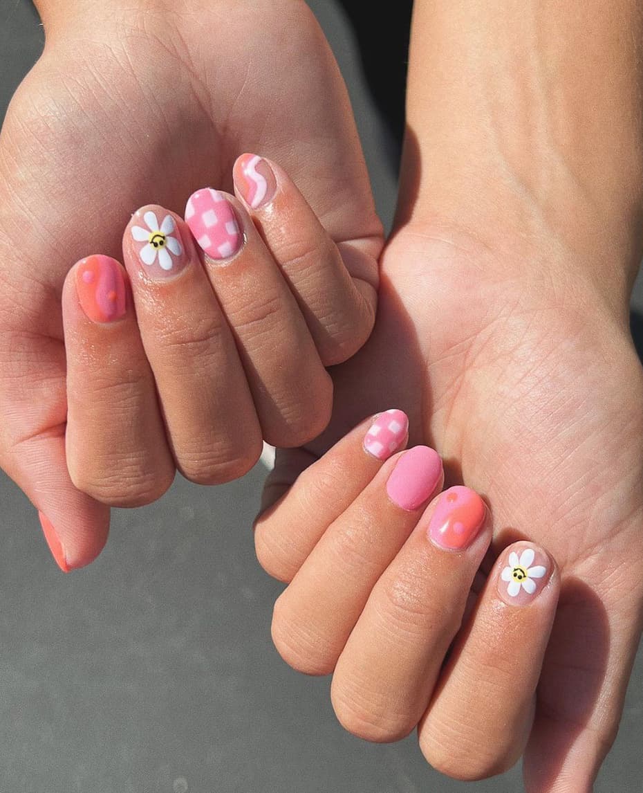 image of a pair of hands with pink and white checkered and daisy retro nail art