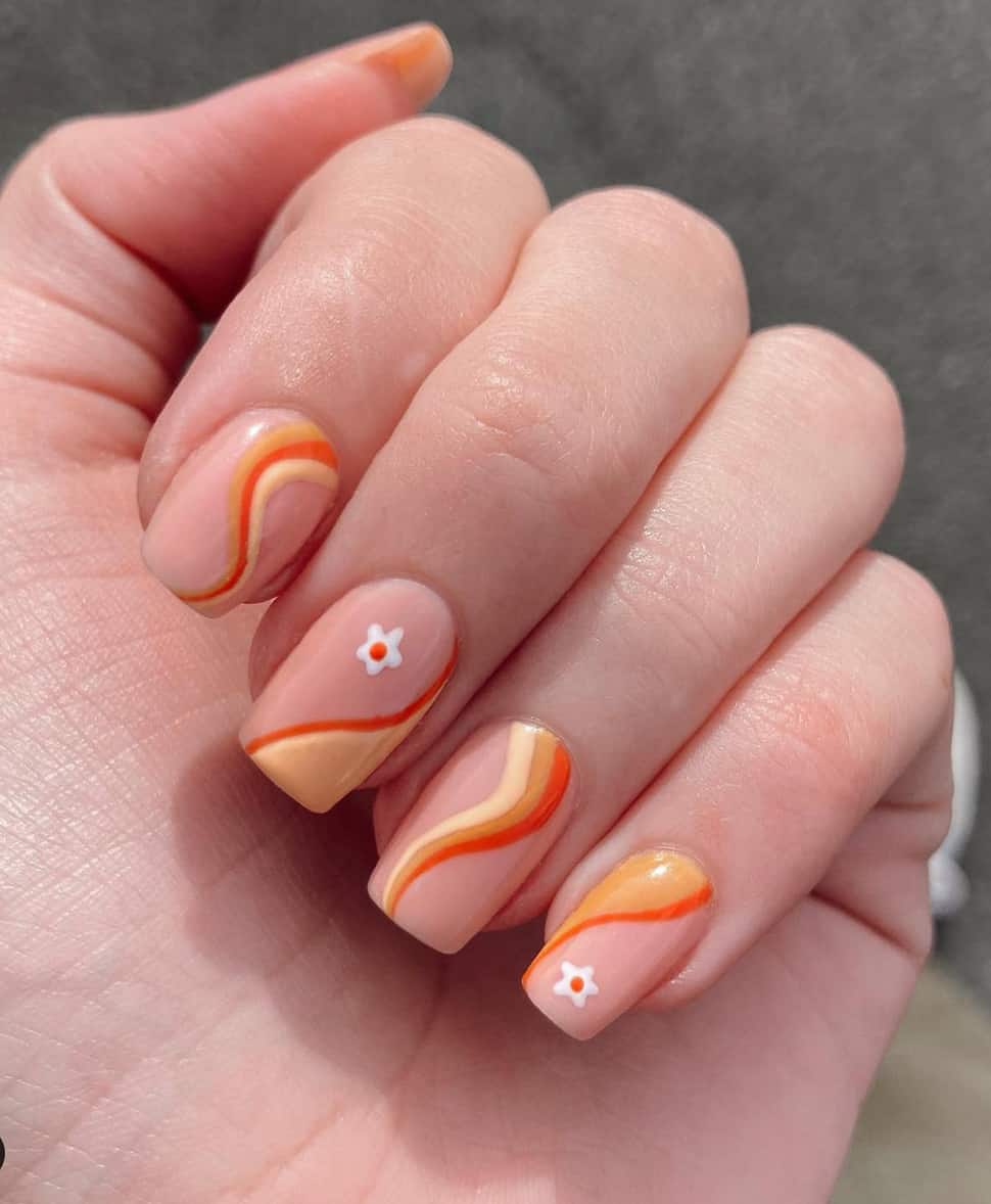 image of a hand with medium length square nails with orange, yellow, and ivory waves and flower art