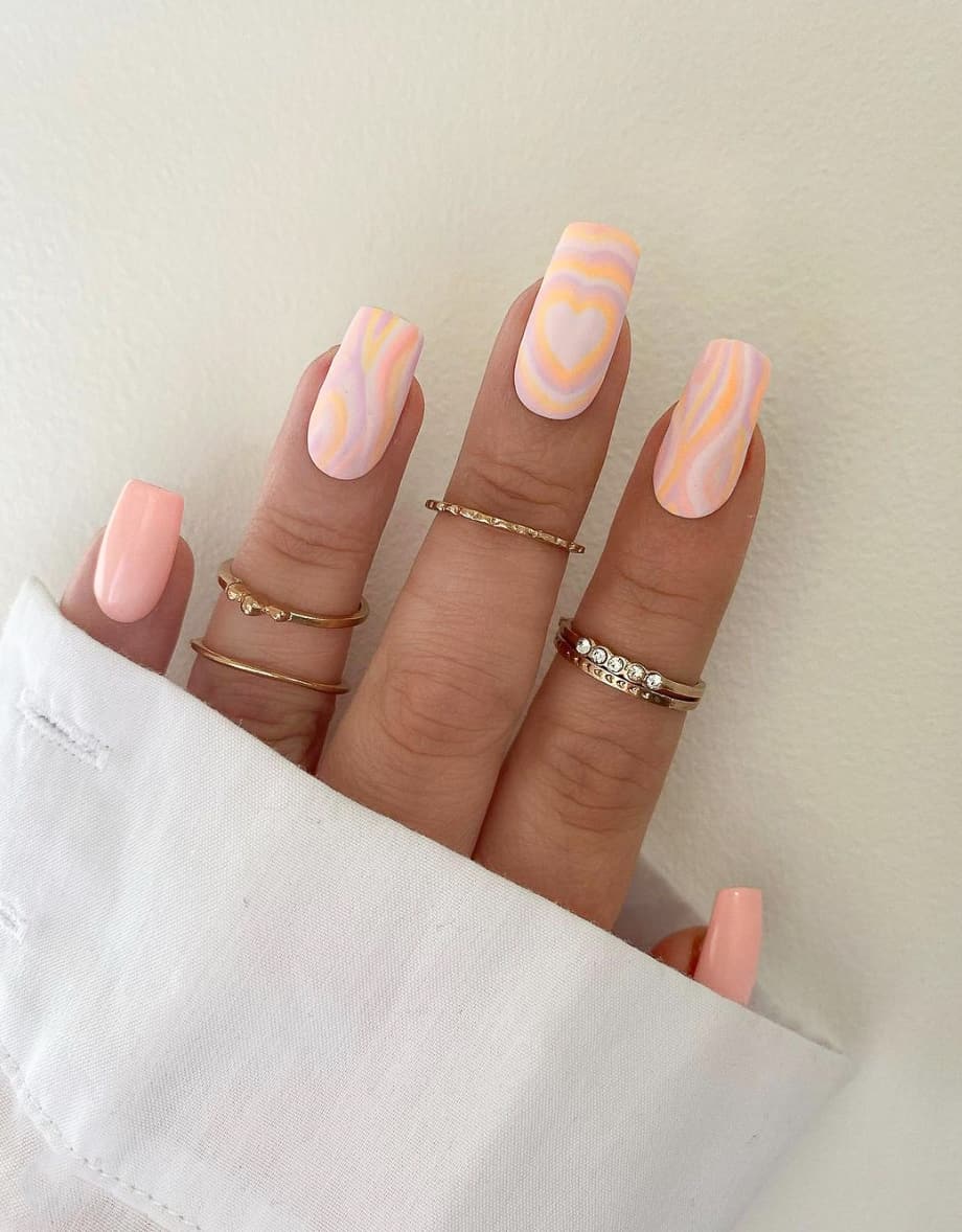 image of a hand with ivory and peach nail art with retro inspired wave designs