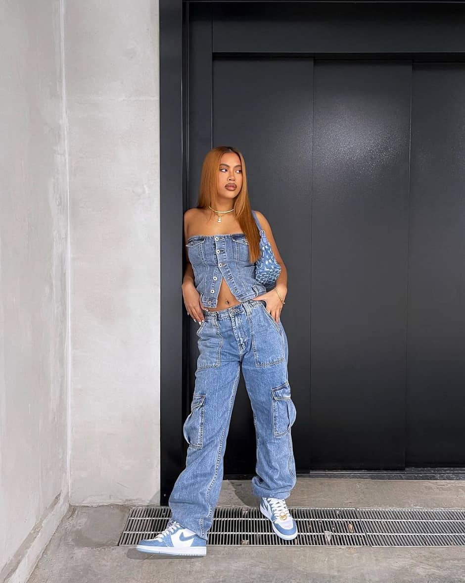 Woman wearing baggy jeans and a denim tube top with sneakers.