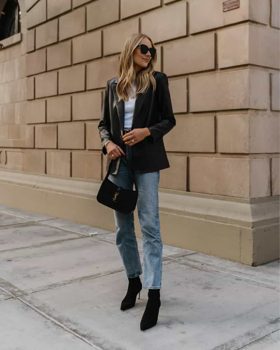 woman wearing a black leather blazer over a white shirt with blue jeans and black pointy ankle boots