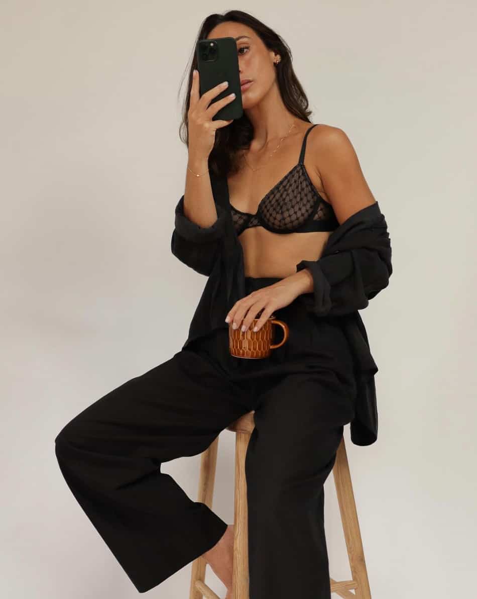 woman wearing a black blazer and black pants with a black lacy bra underneath for a boudoir style shoot