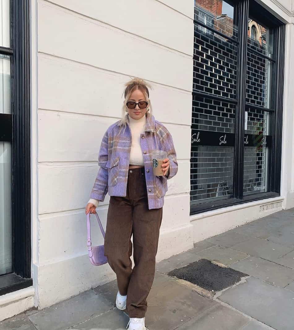 woman wearing a purple plaid cropped shirt jacket over a white top with brown corduroy pants and sneakers