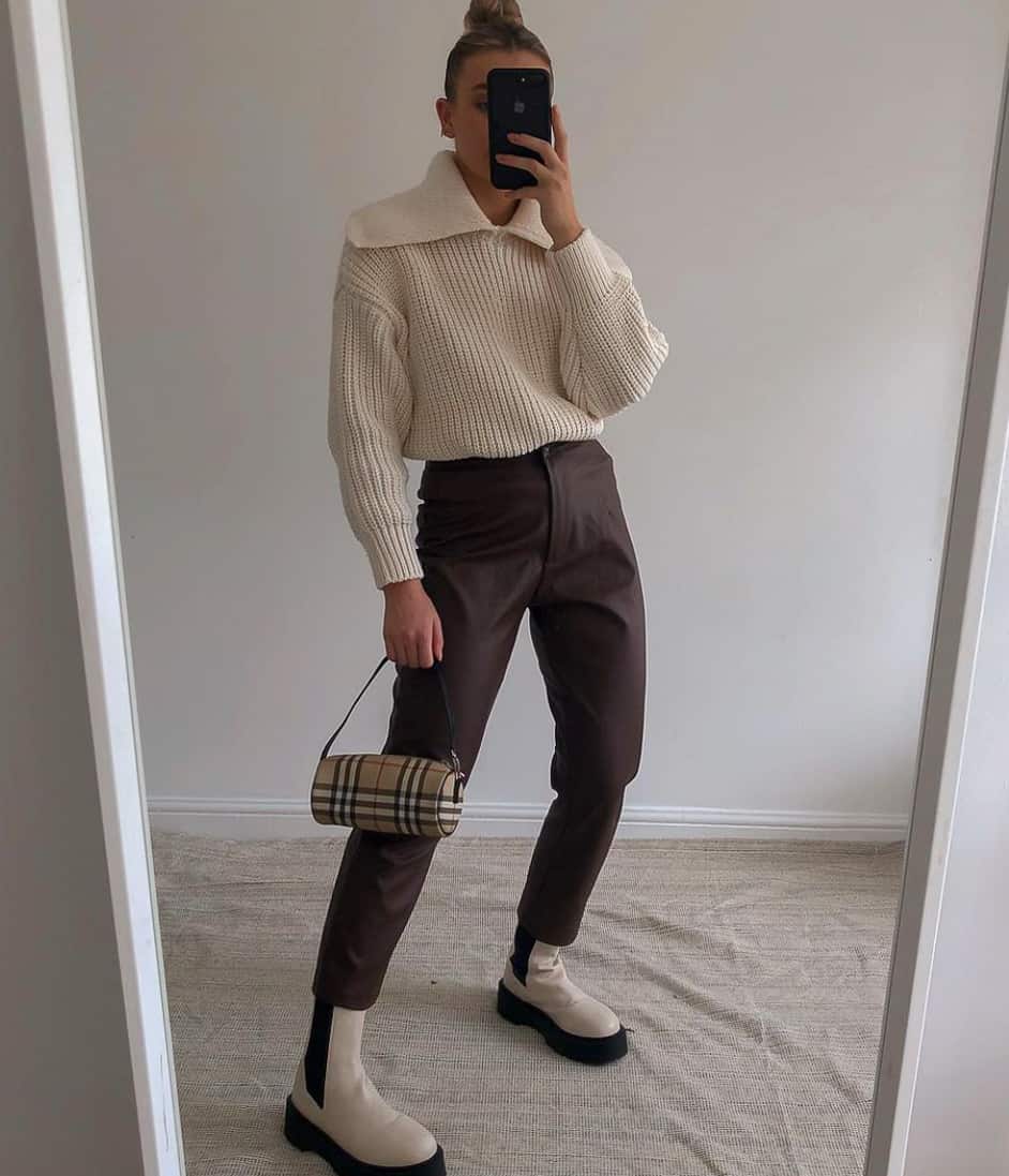woman wearing a knit half zip ivory sweater with brown pants and white lug boots