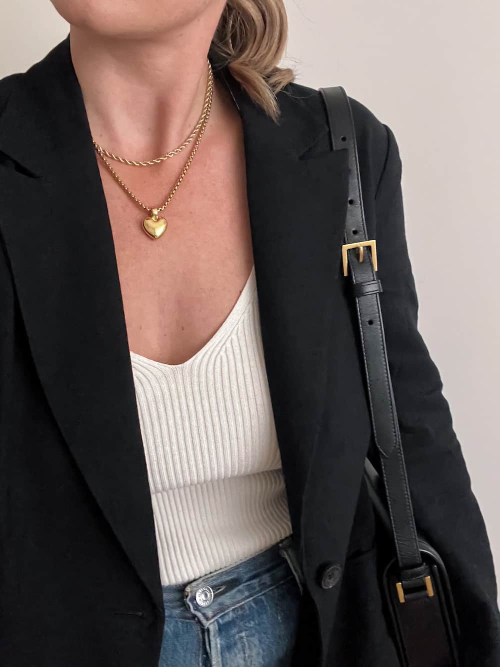 woman wearing a black blazer with an ivory ribbed tank top, jeans, and gold jewelry