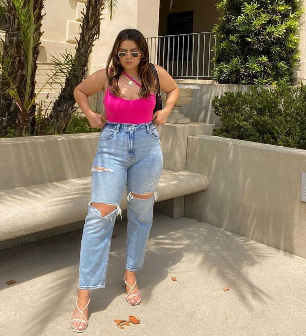 woman wearing a pink tank top with distressed blue jeans and white strappy heeled sandals