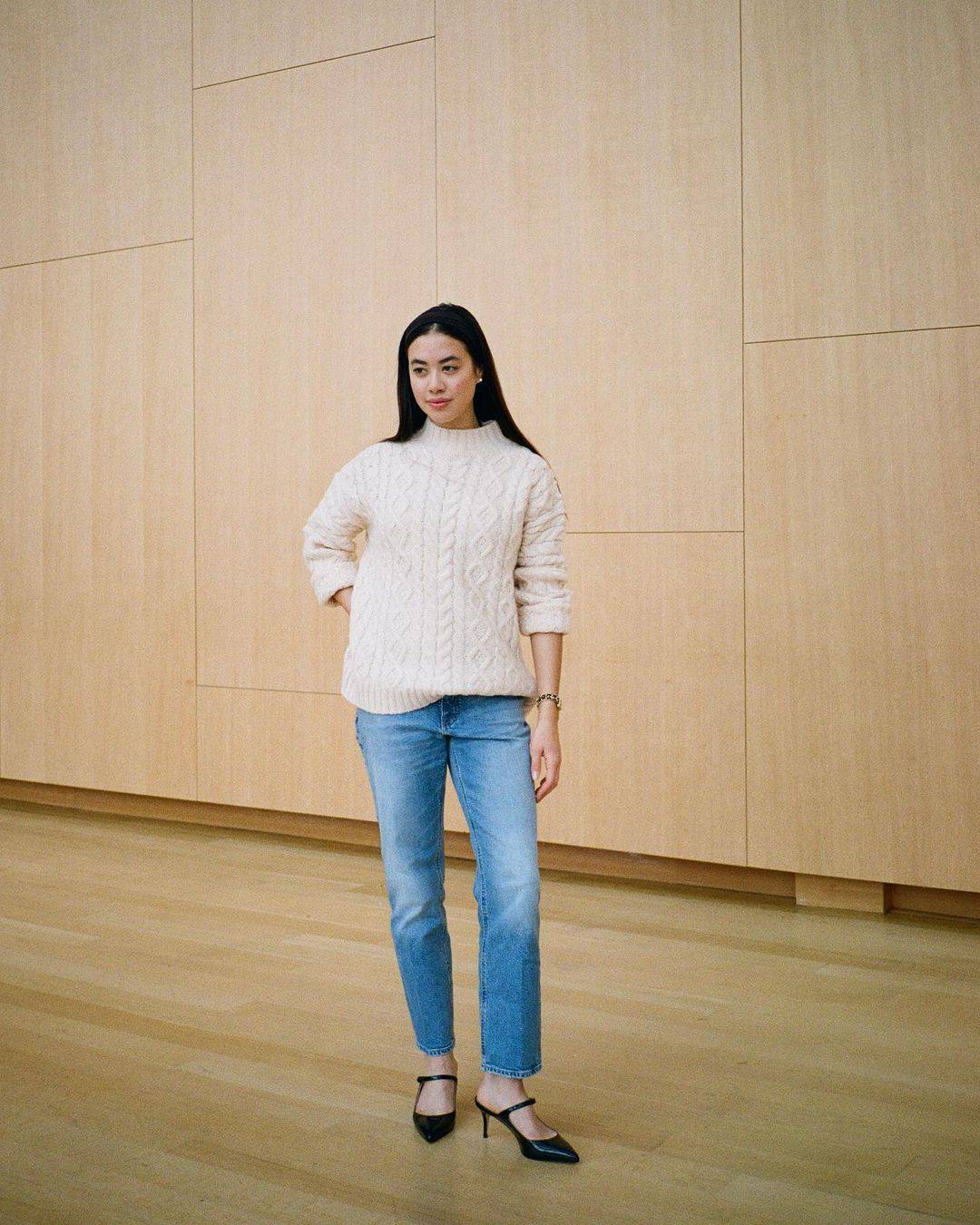 woman wearing a cable knit sweater with straight leg jeans and black heels