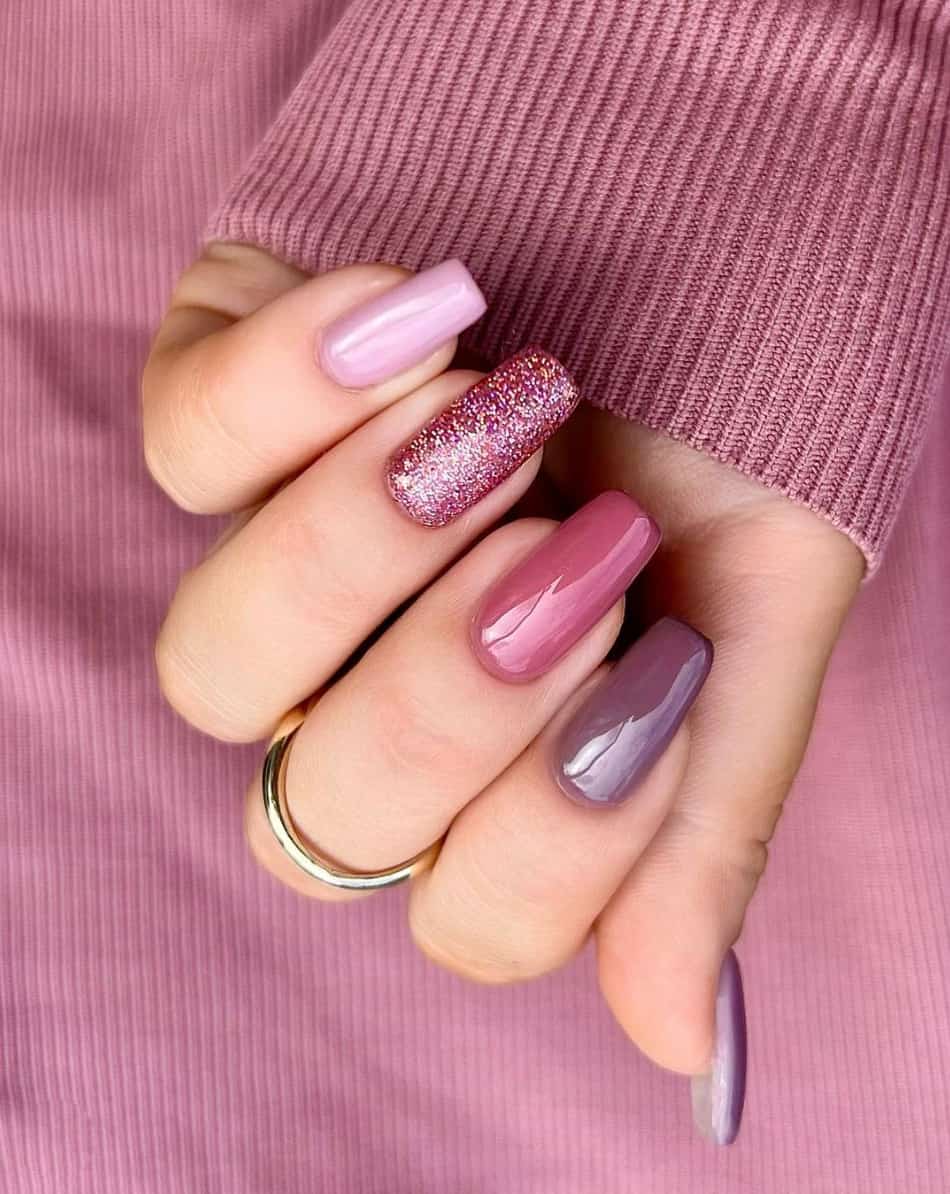 Long, square mauve manicure. One nails is a glittery mauve. The other nails shiny mauve gradient. Each nails is a different shade of mauve.