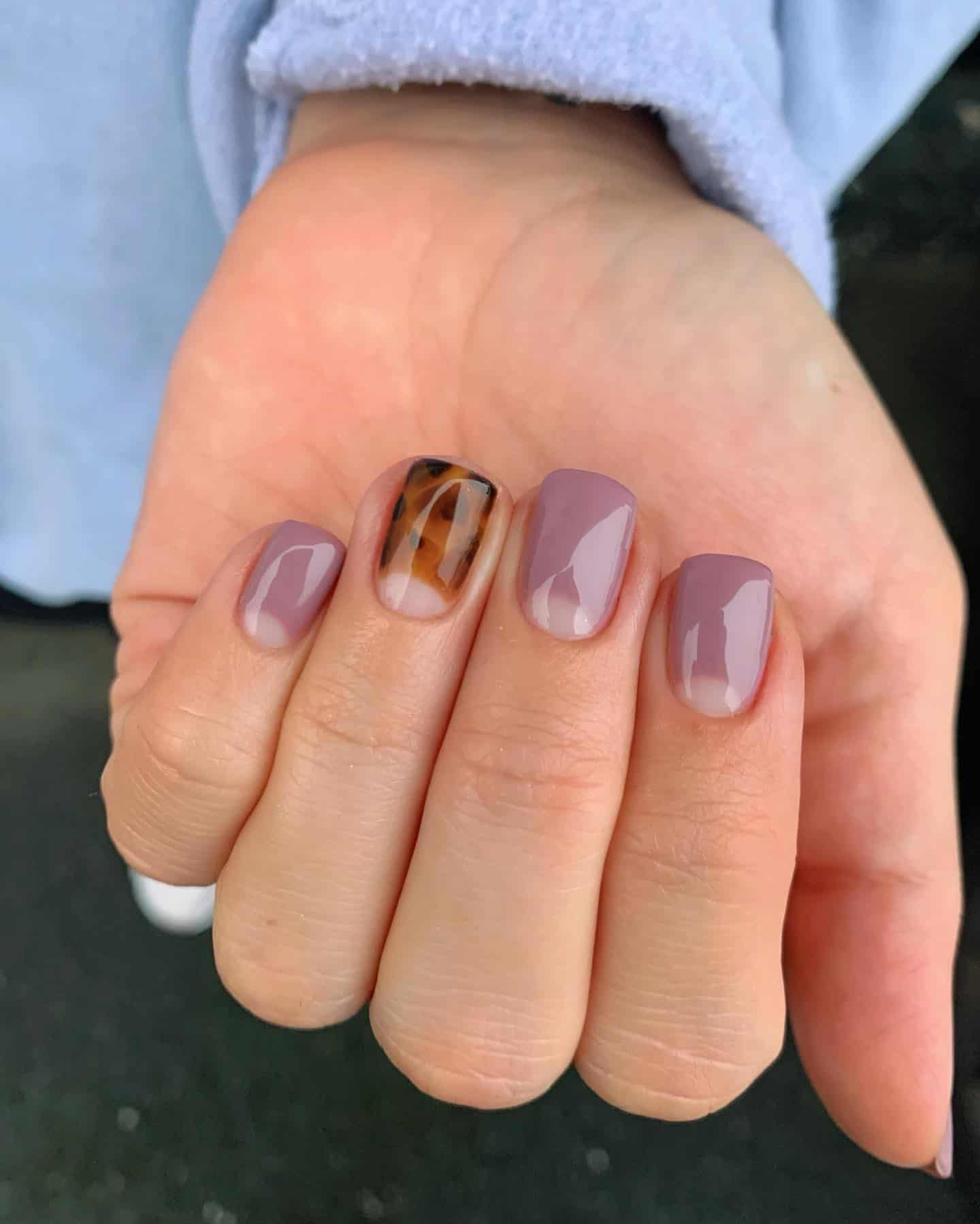 Short, square mauve manicure with a tortoise shell effect on one finger.