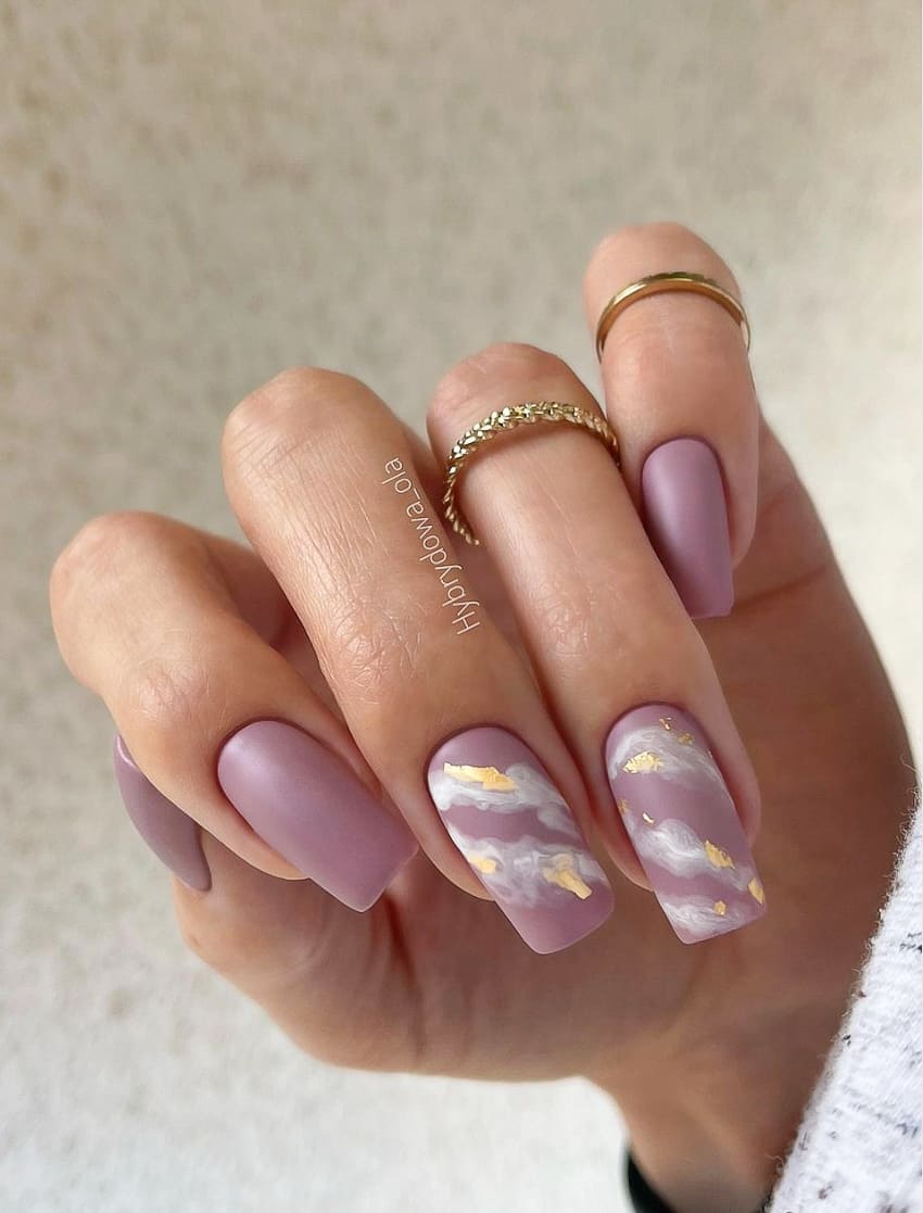 Long, square matte mauve manicure. Two nails have white and gold marbling.
