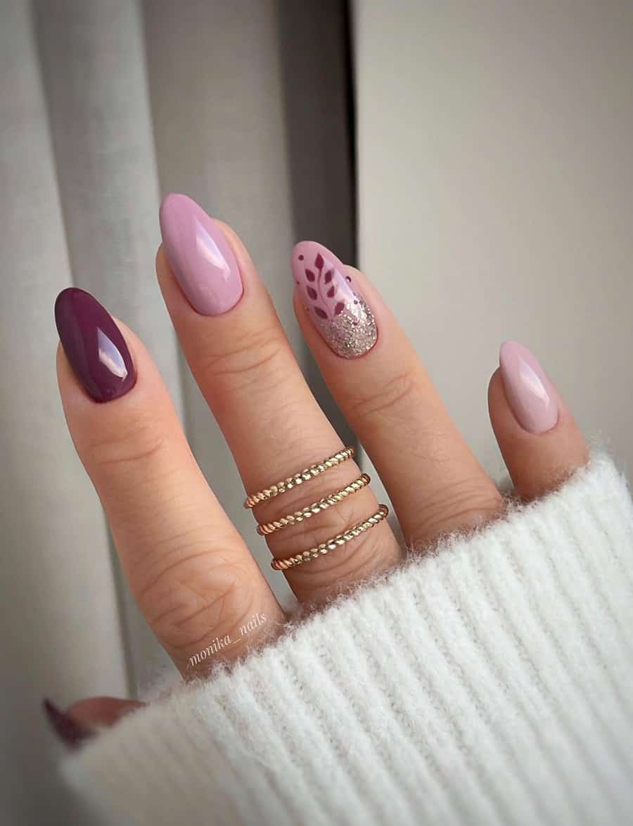 Short, rounded mauve manicure. Two nails are dark purple mauve. Two nails are light pink mauve. One nail is light pink mauve with a dark purple mauve flower and silver glitter.