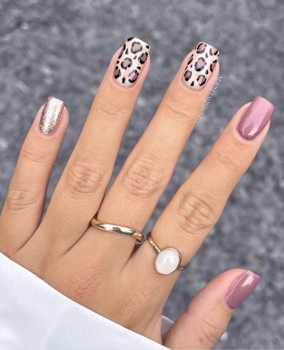 Short, square mauve manicure. Two nails are purple mauve. One nails is rose gold glitter. The last two nails are mauve cheetah print.