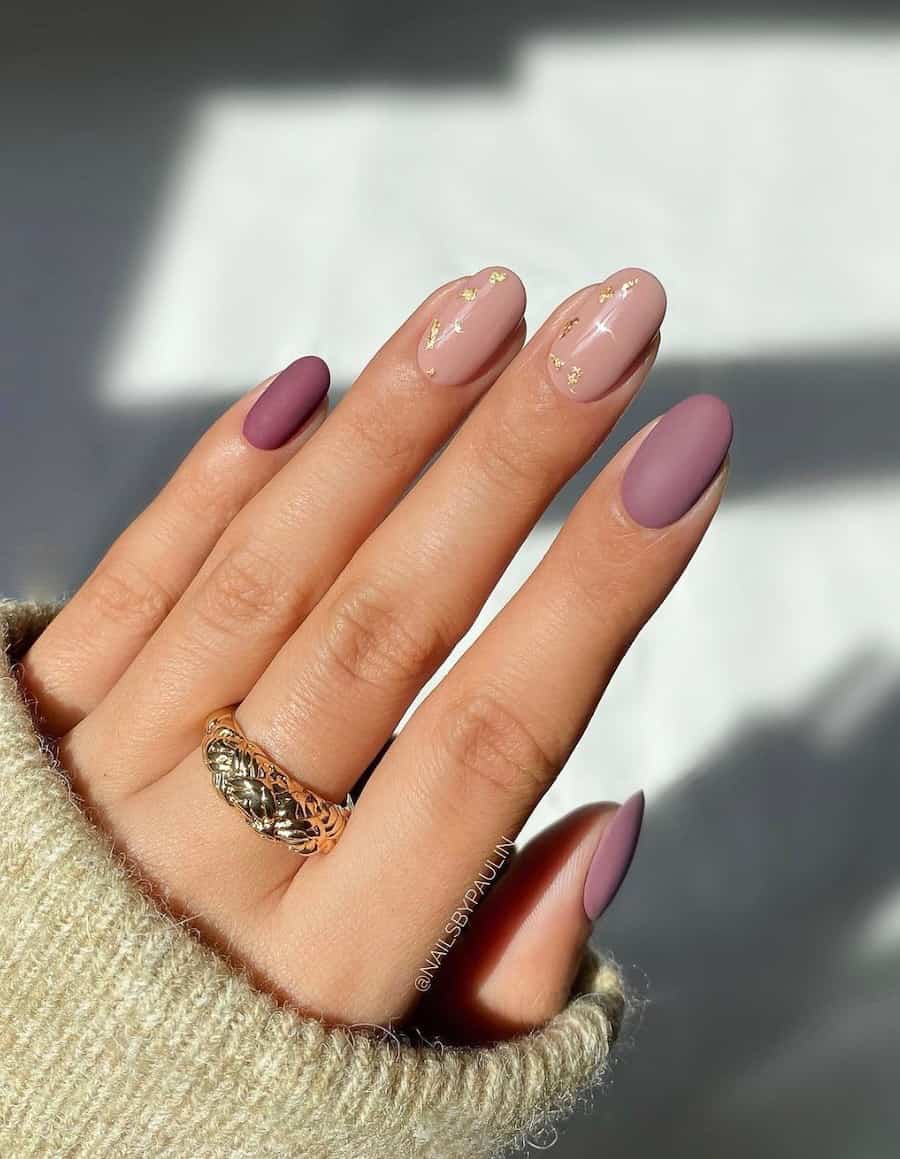 Short, rounded matte mauve manicure. Two nails are a nude mauve with gold glitter. Three nails are darker mauve.