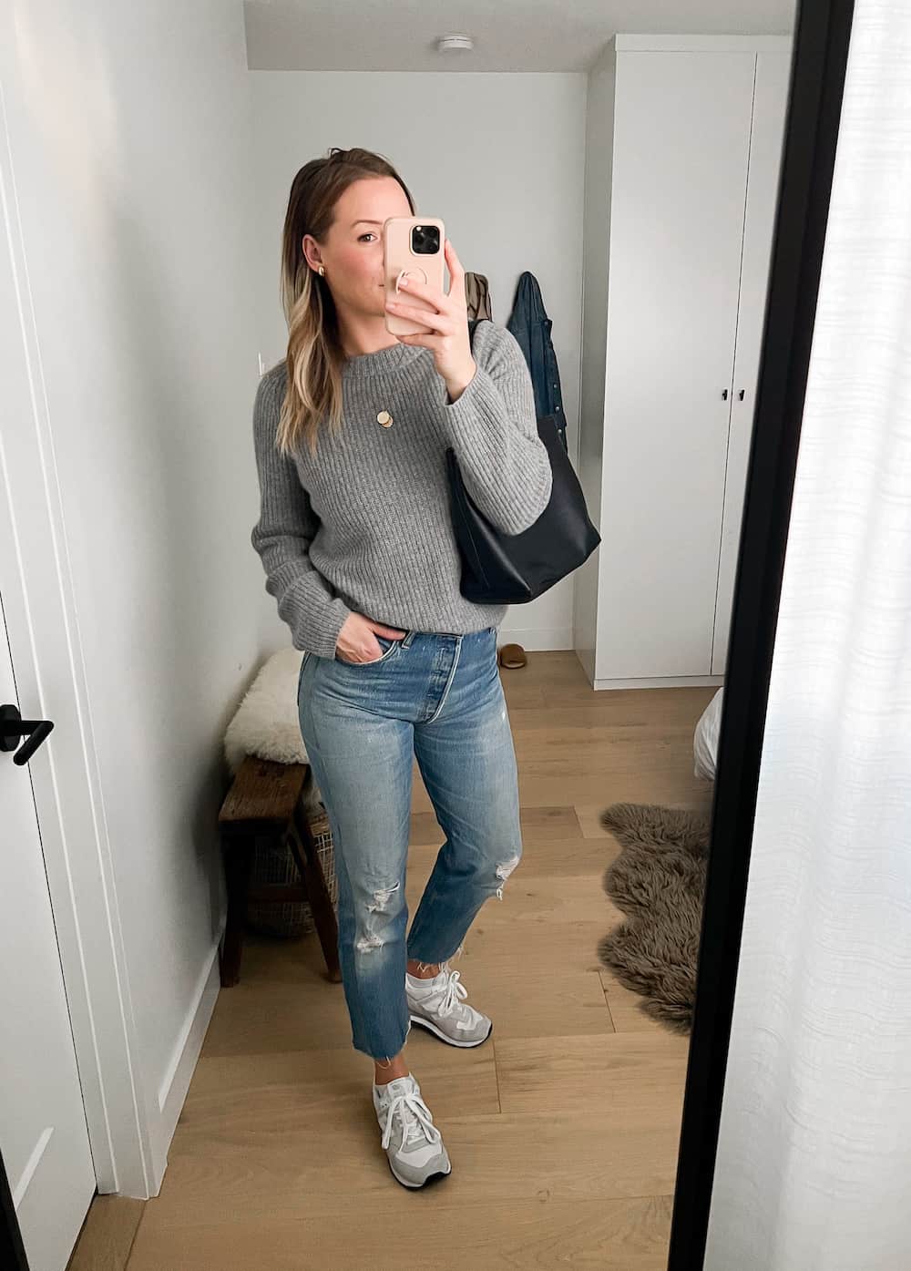 woman wearing a grey cashmere fisherman sweater with distressed jeans and neutral New Balance 574 sneakers