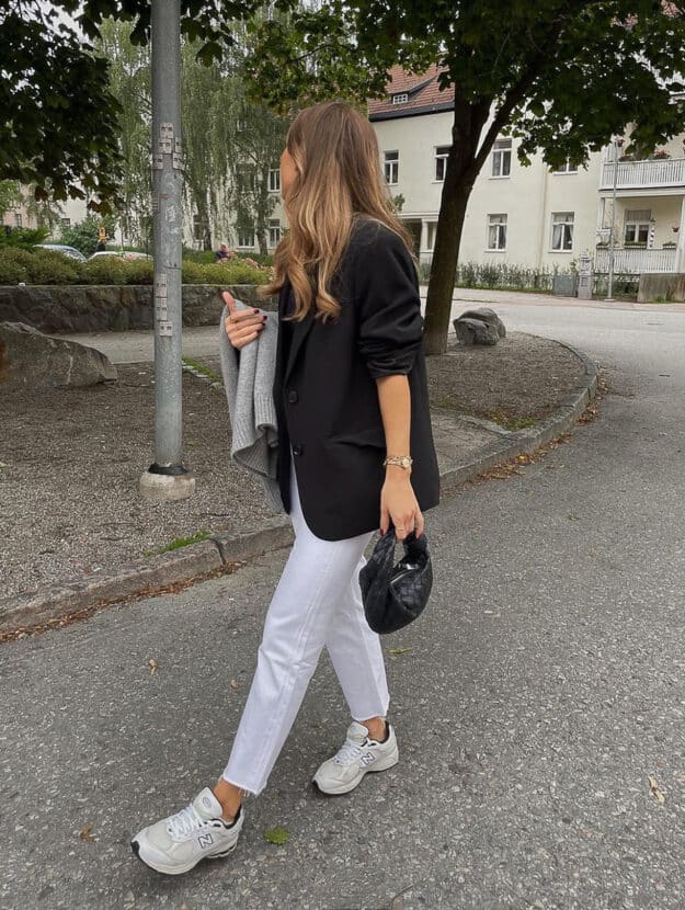 woman wearing a black blazer, white jeans, and New balance sneakers