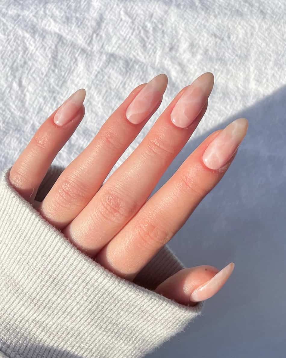 image of a hand with long oval nude nails with a marble design