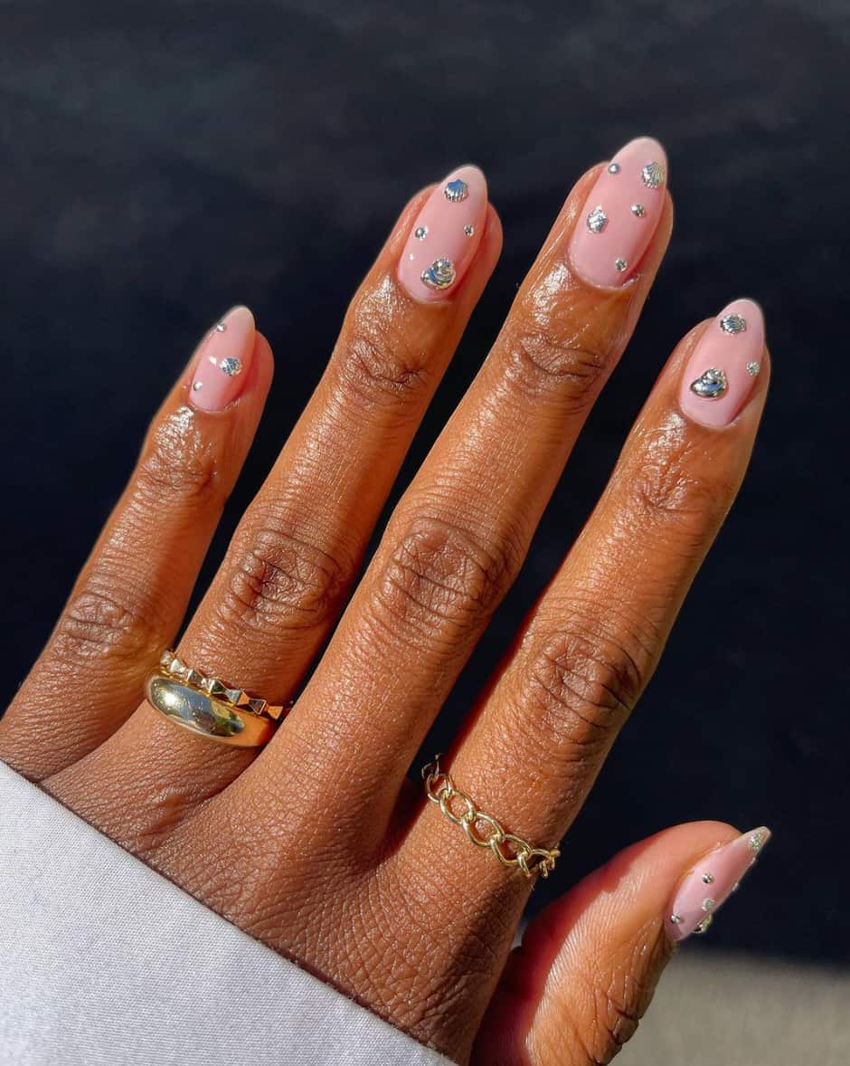 image of a hand with nude pink nails with silver rhinestone accents
